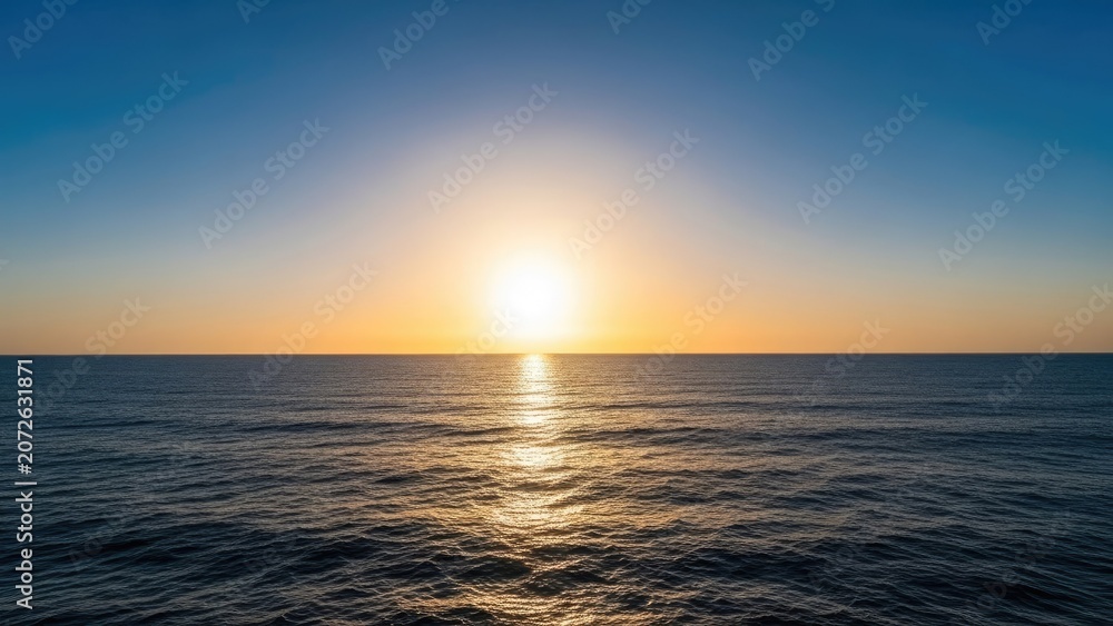 Obraz premium Golden sunset sun reflecting over calm deep blue ocean.