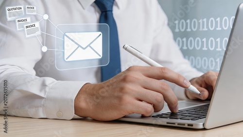 Businessman working on laptop sending email with digital invoice and quotation documents overlay, representing modern office communication and financial administration tasks.