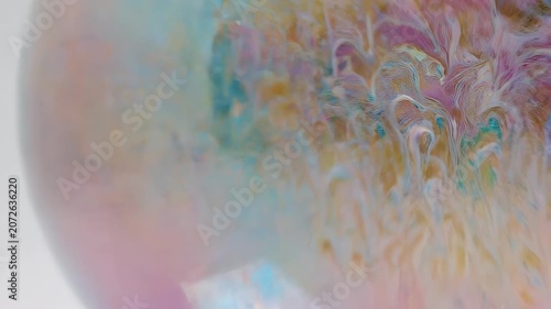 Iridescent Soap Bubble Floating and Reflecting Light on a White Background.