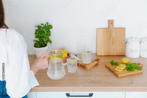 Glass pitcher with lemonade and sliced lemons on a kitchen counter