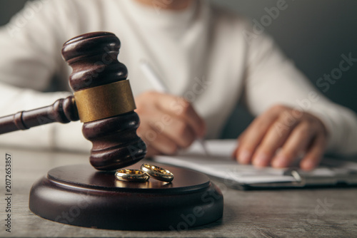Judge gavel and wedding rings on table. Divorce concept.