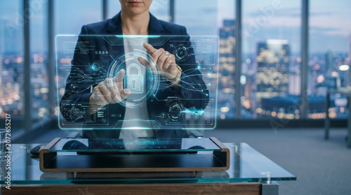 Businesswoman protecting digital data on futuristic holographic screen in modern office