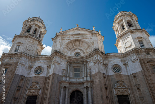Low-angle view of Cadiz Cathedral facade with both Levante and Poniente towers under a clear blue sky in Cadiz, Spain