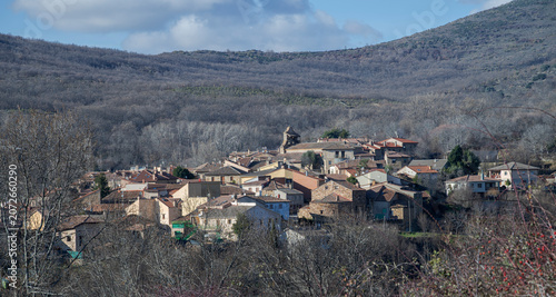 Horcajuelo de la Sierra village with traditional houses in Sierra del Rincón, Madrid, Spain, surrounded by hills and forest under soft daylight.