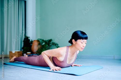 Canvastavla Asian woman practicing yoga cobra pose, strengthening her core and back for flex