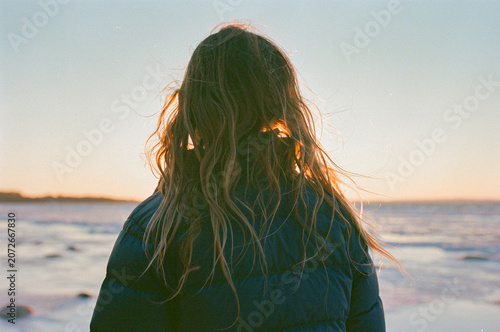 Child in puffer jacket enjoying a winter sunset