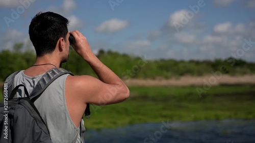 Young man exploring nature with binoculars with copy space