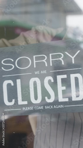 Vertical Screen : Young Asia girl wear face mask turning sign from open to closed sign on glass door cafe after coronavirus quarantine. Owner small business, food and drink, business financial crisis.