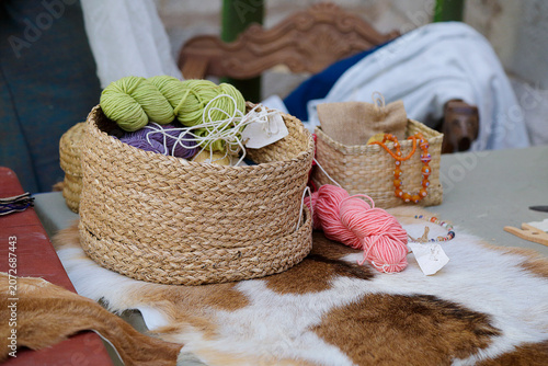 Woven baskets filled with colorful yarn and handmade craft materials displayed on a fur-covered surface.