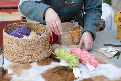 Artisan arranging colorful yarn skeins and woven baskets on a craft table during traditional textile work.