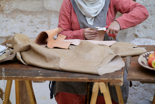 Artisan cutting a piece of leather with scissors at a traditional craft workshop.