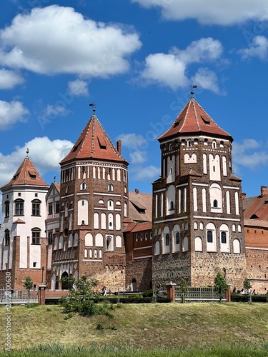 Historic medieval brick castle towers under blue sky with white clouds