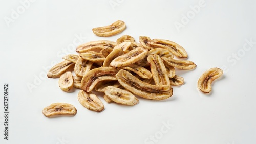 A pile of dried banana chips scattered on a plain white background, studio lighting, view, healthy snack food, organic fruit slices