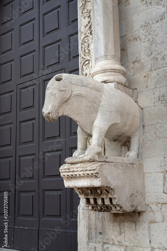 Close-up of Romanesque stone lion sculpture supporting cathedral column at Basilica di San Nicola in Bari, Italy. Historic limestone carving showcasing medieval craftsmanship and Apulian Romanesque ar