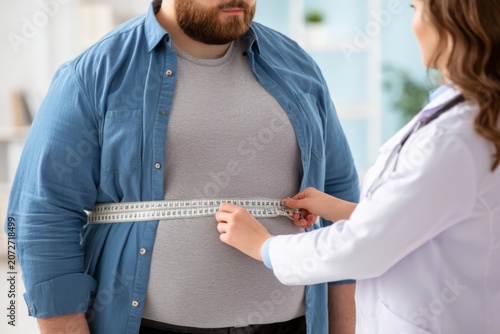 Healthcare professional measuring waist circumference of an overweight man in a clinical setting emphasizing health and fitness awareness for weight management. Generative AI