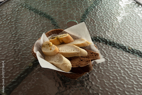Basket of bread placed on a glass table outdoors during the daytime