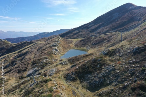 Aerial view of Lago Nero nestled in the rugged Apennine Mountains with rocky slopes, sparse vegetation, and ski lift infrastructure in Abetone Cutigliano, Tuscany, Italy.