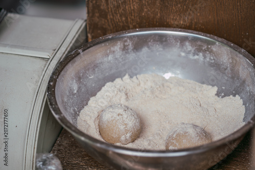 Foto Fresh dough balls resting in a bowl of flour before rolling