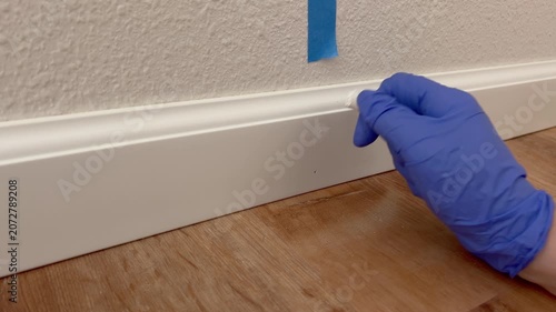 Gloved Hands Sealing Baseboard with Caulking