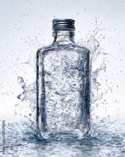 Empty glass bottle with condensation on cracked ice surface