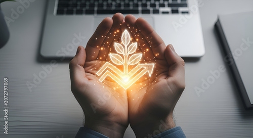 Hands holding glowing plant icon on desk with laptop