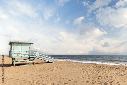 Empty sandy beach with lifeguard tower under blue sky