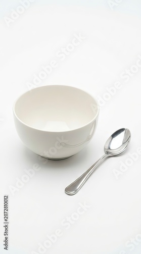 Clean White Ceramic Bowl with Silver Spoon Isolated on White Background for Minimal Kitchenware Concept