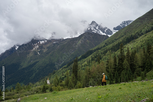 Hikers in the valleys of mist-shrouded snow-capped mountains