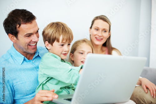 Laptop, family and father laugh with child for educational game, bonding and development in home. Sibling, parents and computer for learning at house with funny meme, teaching kid and reading story