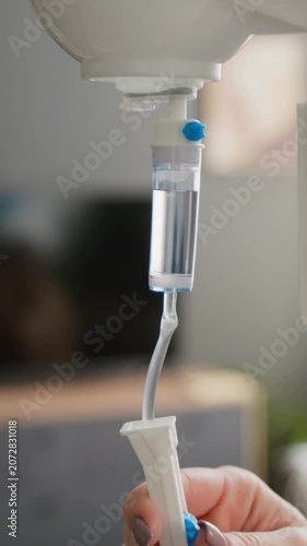 Vertical shot of female nurse adjusting IV drip flow regulator in clinic. Footage healthcare marketing, senior care services, and medical training videos
