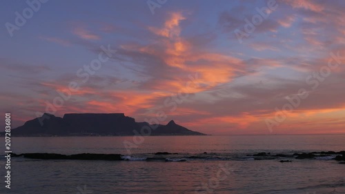4K 25fps footage from Bloubergstrand showcasing the iconic Cape Town skyline with Table Mountain, Devil’s Peak and Lion’s Head across Table Bay under clear South African blue skies.
