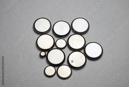 Flat round batteries of different sizes on a gray background