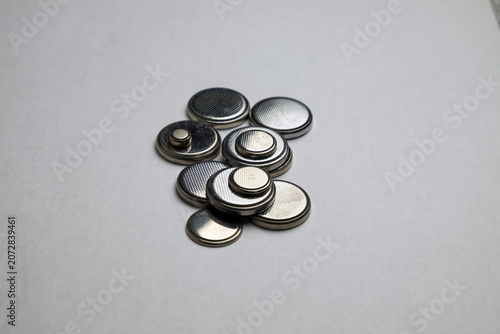A set of shiny silver metal round batteries of various sizes neatly laid out on a surface