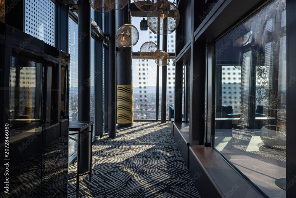 Fototapeta premium Contemporary rooftop bar corridor with large windows and geometric patterned carpet