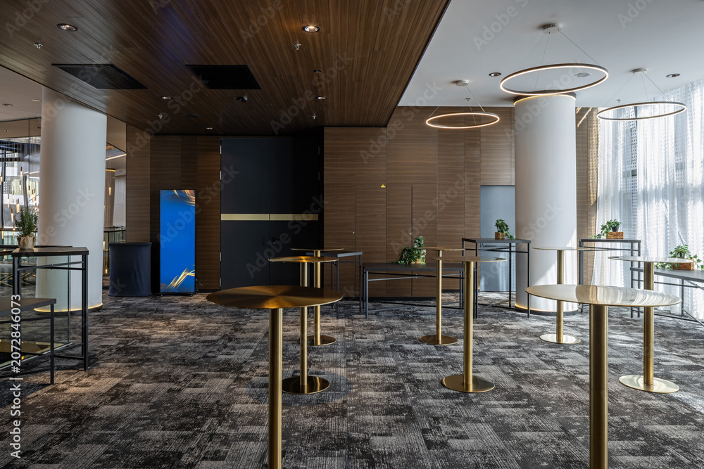 Naklejka premium Modern hotel lobby interior with elegant cocktail tables and contemporary lighting