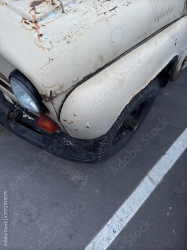 Rusty abandoned car body with heavy corrosion, peeling paint and metal hook detail