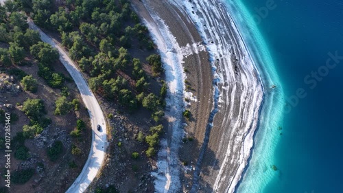 A mesmerizing drone view of Lake Salda’s turquoise waters, its white shoreline, and the winding road right next to it blending into the forest.