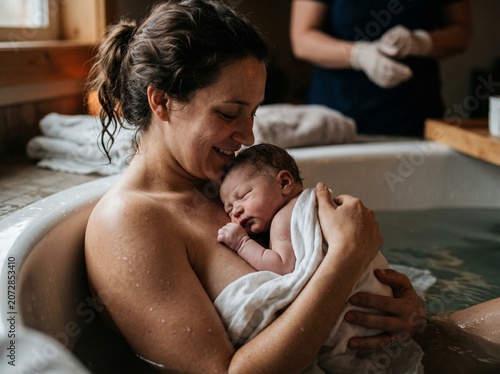 newborn infant resting peacefully on mothers chest post water birth moment

