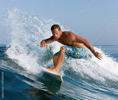 a young man surfing on a blue ocean wave. 