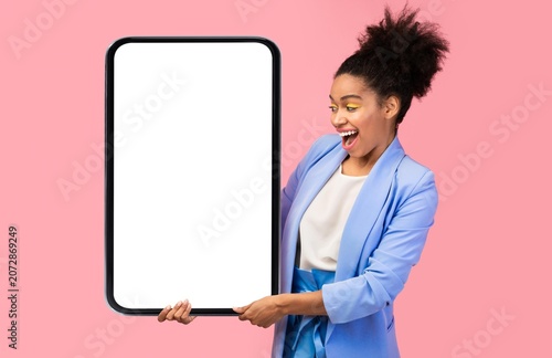 Foto Smiling African American Woman Holding Blank Smartphone With Empty Screen, Displaying Mockup In Studio Against Pink Background, Showing Excitement In Concept Of Technology And Innovation