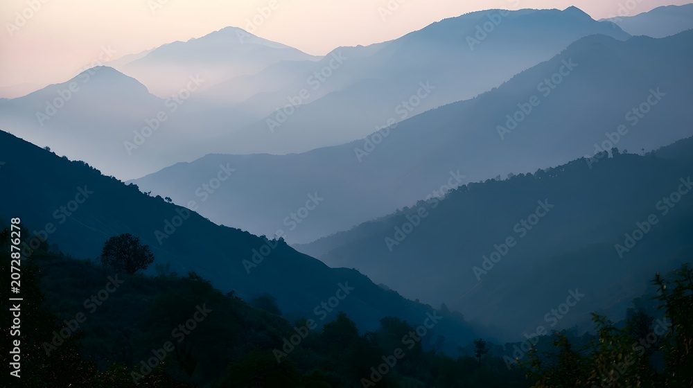 Fototapeta premium A quiet misty mountain range is bathed in gentle dawn light as soft shadows dance across the rugged peaks