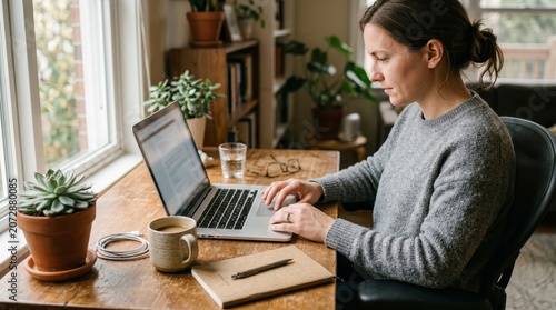 Woman working on laptop at home desk.