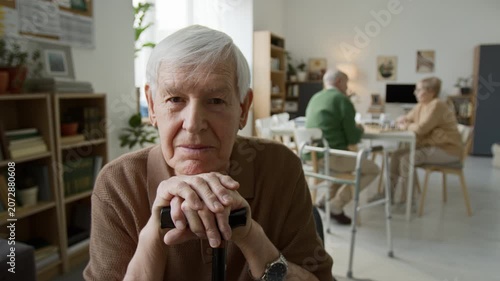 Portrait of senior man leaning on walking cane in nursing home and looking at camera. Clip senior care, retirement community marketing and geriatric healthcare ads