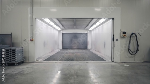 Paint spray booth interior stands clean and empty in an automotive refinishing workshop waiting for a vehicle arrival.