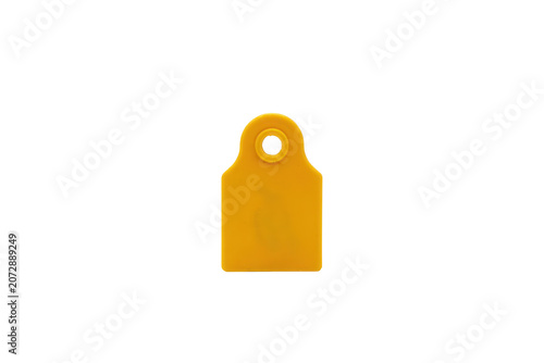 A single yellow plastic ear tag for livestock identification, featuring a circular hole at the isolated on a plain black background