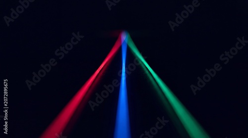 Three ultra-thin strand composed of vibrant red, blue, and green fibres rays, isolated against a deep black background. Shot in extreme perspective