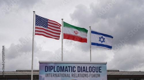 USA, Iran, Israel flags waving side by side against a cloudy sky, representing diplomatic attempts at communication, international relations, and ongoing geopolitical challenges