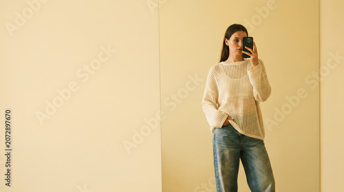 Young woman taking a mirror selfie in a minimalist bright room