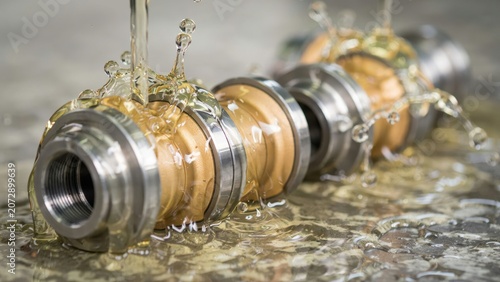 Metal shaft being lubricated with oil splashing in an industrial workshop