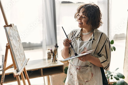 фотографія Curly-haired woman immersed in painting, expressing her creativity in a stylish apartment